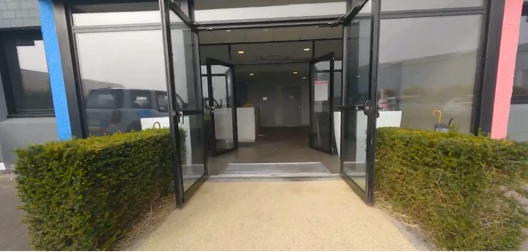 Vol en drone FPV vers l’entrée vitrée d’un bâtiment d’entreprise