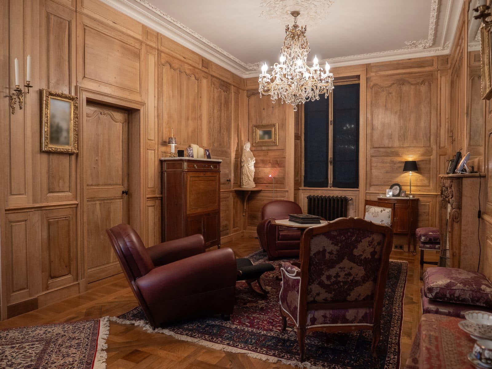 Salon boisé avec lustre en cristal et fauteuils club