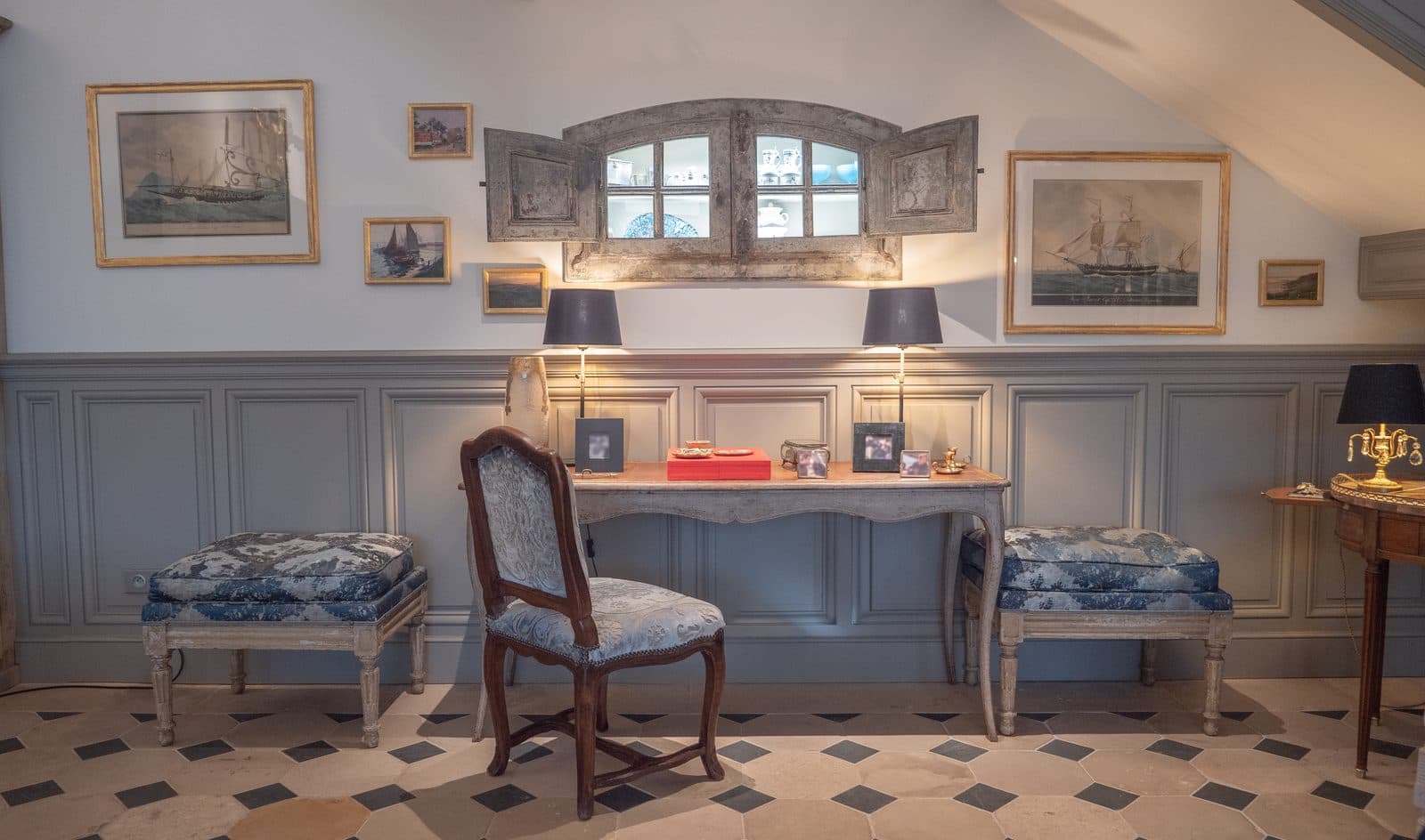 Bureau ancien sous une fenêtre ornée de tableaux de marine