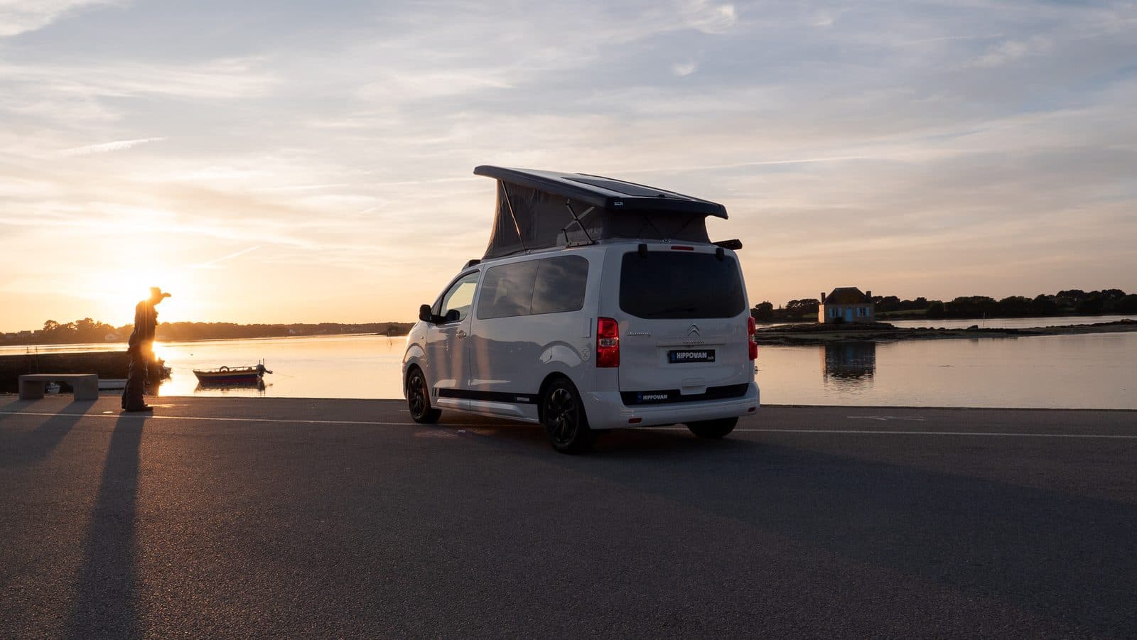 Van aménagé toit relevé au coucher du soleil sur la côte