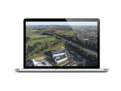 Vue aérienne par drone d’un site d’entreprise entouré de champs, sur un écran d’ordinateur