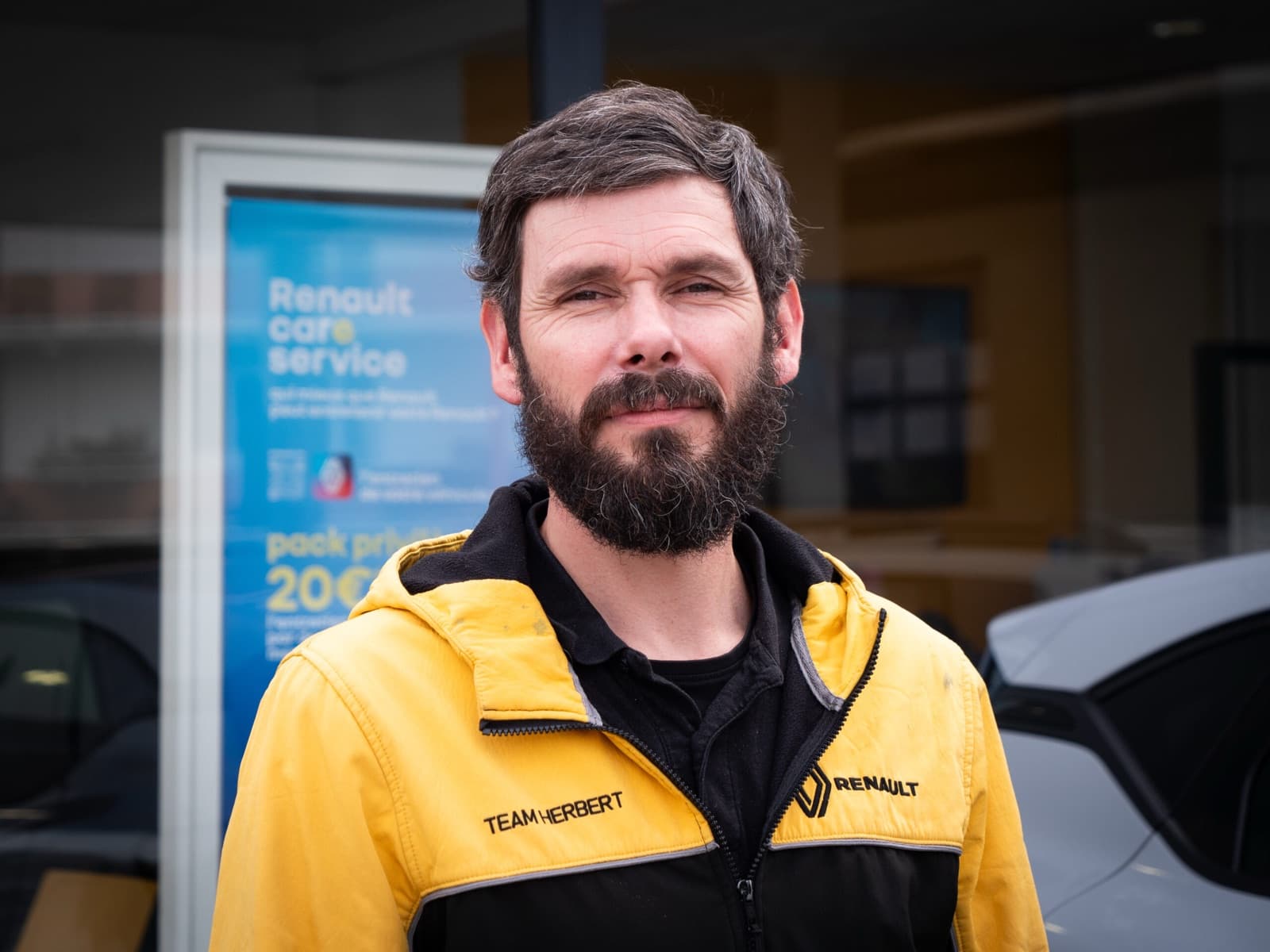 Portrait d’un collaborateur du Garage Herbert en veste Renault jaune devant la concession